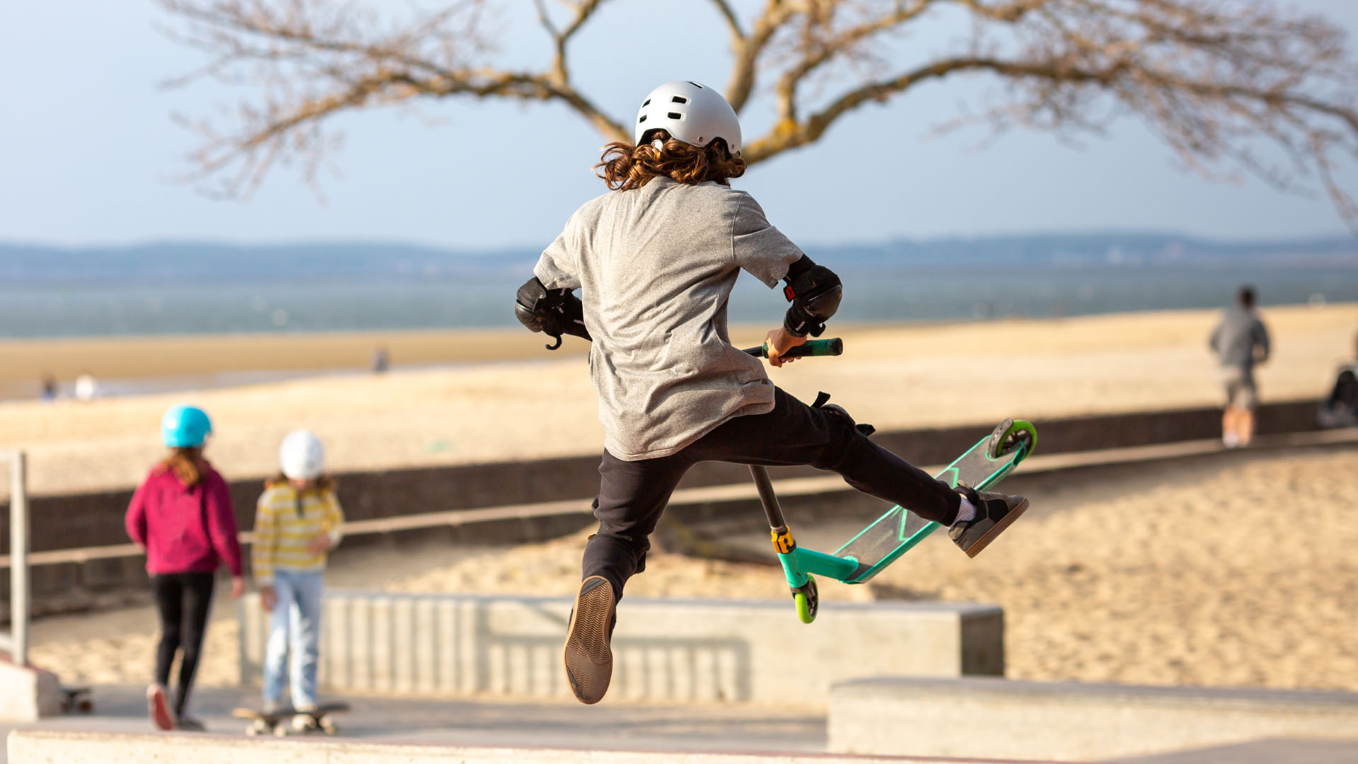 Young person jumping in a skatepark with a scooter